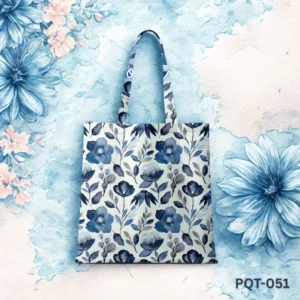 Blue Flora Canvas tote bag (PQT-051) featuring an all-over vintage-style floral print with blue and grey flowers and leaves on a light cream background, with matching printed handles, displayed upright against a dreamy blue and white watercolor floral backdrop.