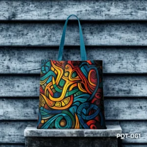 Tribal Fusion Tote Bag (PQT-061) featuring a vibrant, abstract tribal-inspired design with flowing lines and bold shapes in yellow, orange, red, blue, and green on a dark background, with teal handles, displayed upright on a concrete ledge against a dark blue wooden slat wall.