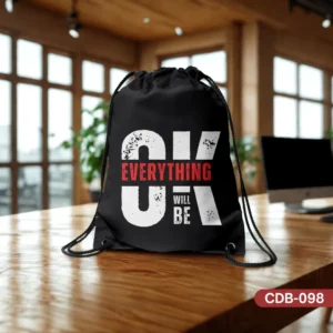 Black Positive Pulse Drawstring Bag (CDB-098) with "OK EVERYTHING WILL BE" typographic design, shown on a wooden desk in an office setting.