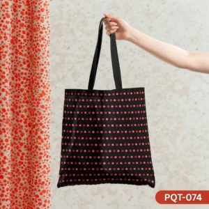 Red Dot Remix Tote Bag (PQT-074) featuring a black background with an all-over pattern of evenly spaced red and pink polka dots, with black handles, held by a hand against a light speckled wallpaper and a red and white dotted curtain.
