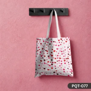 Love Drizzle Tote Bag (PQT-077) featuring a white background with an all-over print of scattered small hearts in various shades of red and pink, with white handles, hanging from a dark wooden peg rack against a textured pink wall.