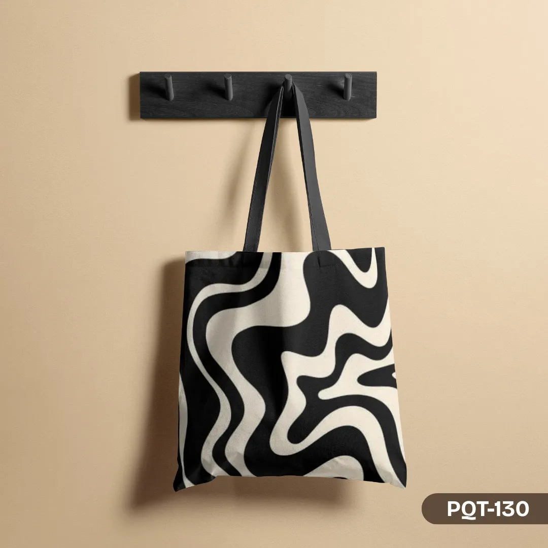 "Dynamic Flow Tote Bag (PQT-130) with a black and white abstract wave pattern hanging on a wall hook."