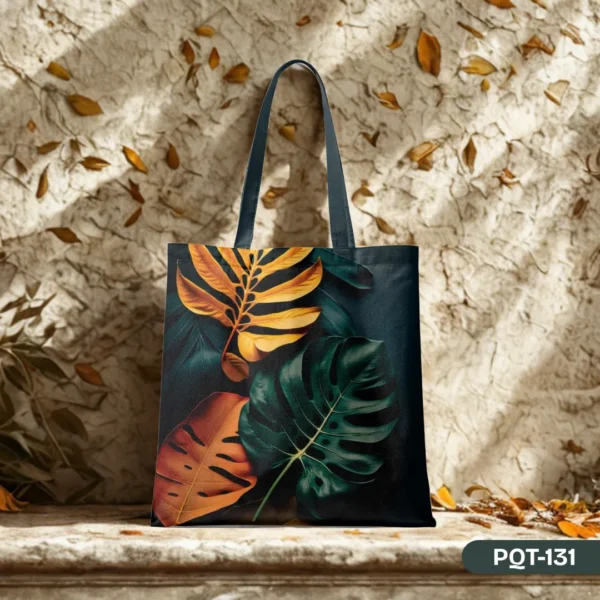 "The Verdant Glow Tote Bag (PQT-131) showcasing a rich botanical print of gold, green, and rust-colored leaves, elegantly displayed against a textured, sun-dappled wall with scattered autumn leaves."
