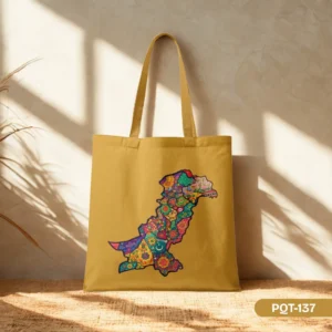 The Jashn-e-Rang Tote Bag (PQT-137) featuring a colorful, intricately patterned map of Pakistan on a mustard yellow background, with matching straps, displayed in a warmly lit setting