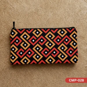 CMP-028 Sunstone Maze Makeup Pouch showcasing its vibrant red, orange, and black geometric pattern, laid flat on a textured light brown background. The black zipper pull is visible on the left