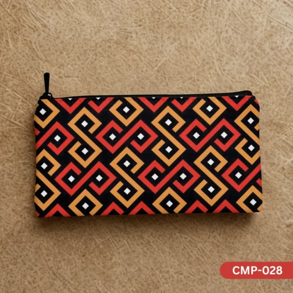 CMP-028 Sunstone Maze Makeup Pouch showcasing its vibrant red, orange, and black geometric pattern, laid flat on a textured light brown background. The black zipper pull is visible on the left