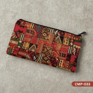 The Nomad's Fire Makeup Pouch with a rich red and orange Kilim rug patchwork pattern, shown on a textured beige background.